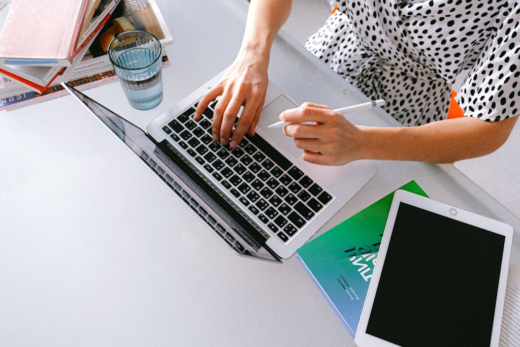 A woman works on a laptop with a tablet in a modern home office setup.